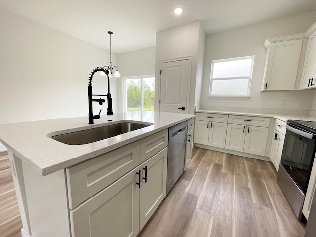 142 Guava Pass, Ocklawaha, FL 32179 - kitchen with stainless steel appliances, a sink, light wood-type flooring, light stone counters, and a kitchen island with sink