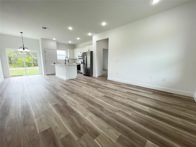 142 Guava Pass, Ocklawaha, FL 32179 - unfurnished living room featuring a chandelier, baseboards, recessed lighting, light wood-style floors, and a sink