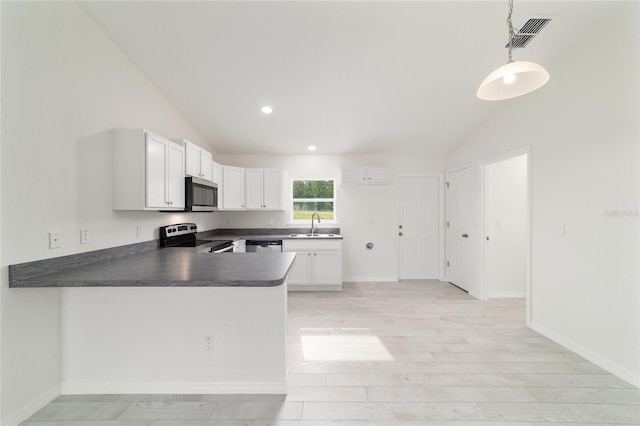 37 Teak Run, Ocala, FL 34472 - kitchen featuring appliances with stainless steel finishes, vaulted ceiling, dark countertops, a peninsula, and white cabinetry