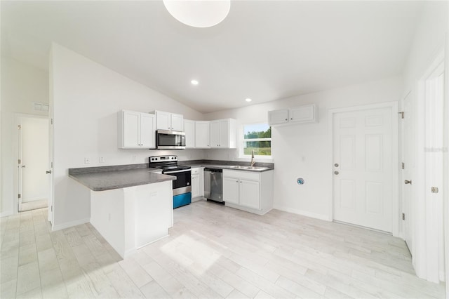 37 Teak Run, Ocala, FL 34472 - kitchen with appliances with stainless steel finishes, a peninsula, dark countertops, lofted ceiling, and white cabinetry