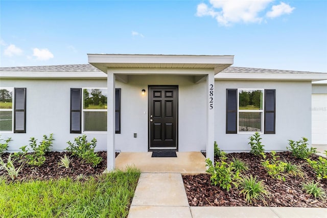 14690 SW 24th Pl, Ocala, FL 34481 - view of exterior entry featuring stucco siding, an attached garage, and a shingled roof