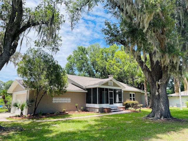 4609 NE 7th St, Ocala, FL 34470 - rear view of property featuring a sunroom, an attached garage, and a yard