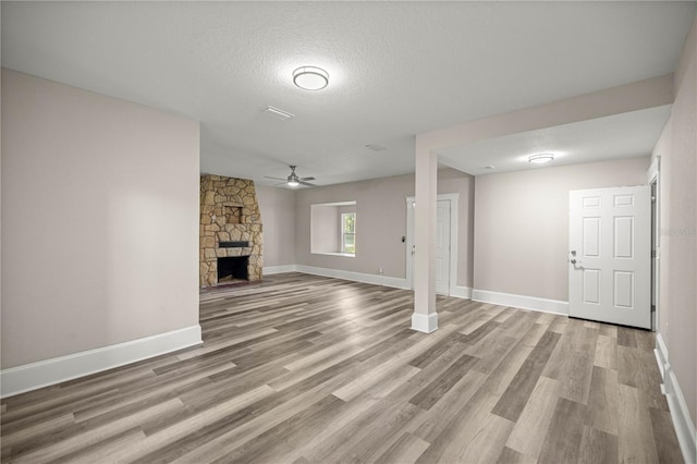 4609 NE 7th St, Ocala, FL 34470 - unfurnished living room with ceiling fan, wood finished floors, a stone fireplace, and a textured ceiling