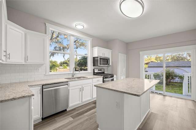 4609 NE 7th St, Ocala, FL 34470 - kitchen with stainless steel appliances, a center island, white cabinets, light stone counters, and backsplash