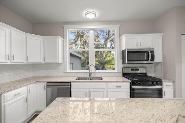 4609 NE 7th St, Ocala, FL 34470 - kitchen featuring stainless steel appliances, white cabinets, backsplash, and light stone countertops