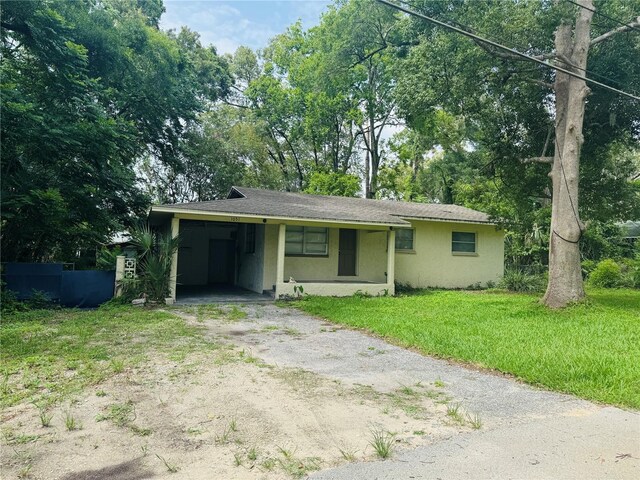 1051 SE 28th Rd, Ocala, FL 34471 - view of front of house with driveway, stucco siding, a front lawn, an attached carport, and view of scattered trees