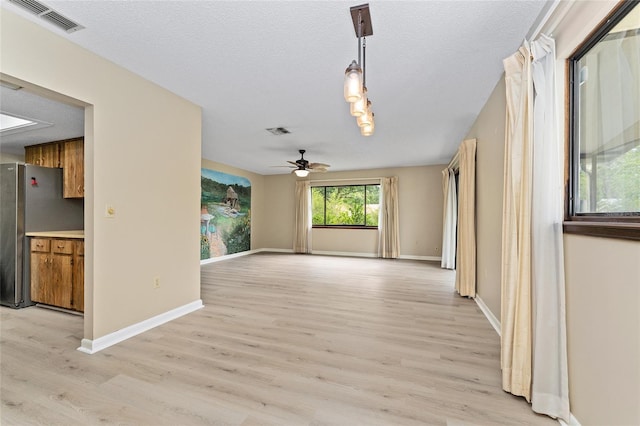 10012 SW 88th Ct, Ocala, FL 34481 - unfurnished living room with light wood-style floors, ceiling fan, a textured ceiling, and baseboards