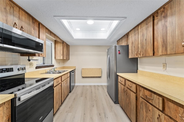 10012 SW 88th Ct, Ocala, FL 34481 - kitchen with stainless steel appliances, light wood-style floors, a sink, light countertops, and a textured ceiling
