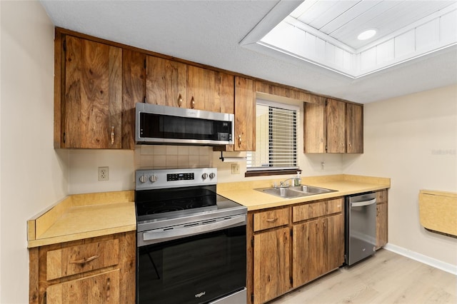 10012 SW 88th Ct, Ocala, FL 34481 - kitchen with stainless steel appliances, a sink, brown cabinets, and light wood finished floors