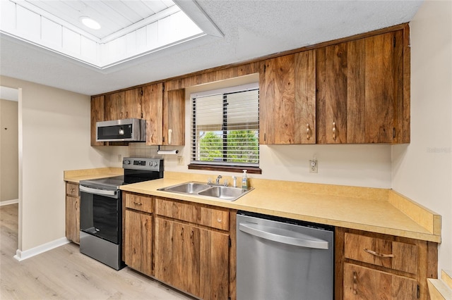 10012 SW 88th Ct, Ocala, FL 34481 - kitchen with stainless steel appliances, a sink, light wood finished floors, and brown cabinetry