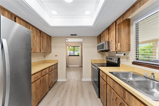 10012 SW 88th Ct, Ocala, FL 34481 - kitchen featuring stainless steel appliances, a sink, light wood-type flooring, light countertops, and brown cabinets