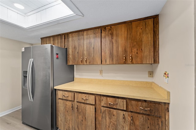 10012 SW 88th Ct, Ocala, FL 34481 - kitchen with stainless steel refrigerator with ice dispenser, brown cabinets, light countertops, and light wood finished floors