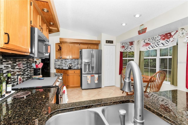 10806 SW 86th Ave, Ocala, FL 34481 - kitchen featuring stainless steel appliances, backsplash, brown cabinetry, vaulted ceiling, and dark stone counters