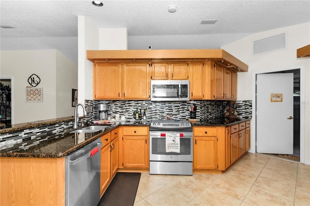 10806 SW 86th Ave, Ocala, FL 34481 - kitchen featuring stainless steel appliances, a sink, a peninsula, dark stone counters, and decorative backsplash