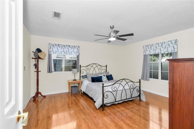 10806 SW 86th Ave, Ocala, FL 34481 - bedroom featuring light wood finished floors, a textured ceiling, baseboards, and ceiling fan