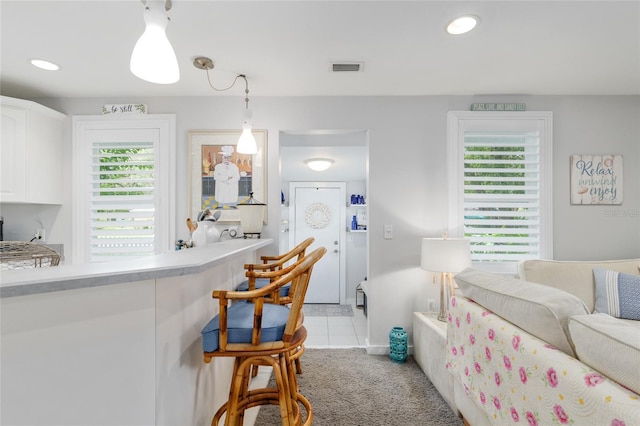 12335 SE 130th Ct, Ocklawaha, FL 32179 - kitchen featuring white cabinetry, light countertops, hanging light fixtures, light carpet, and light tile patterned flooring