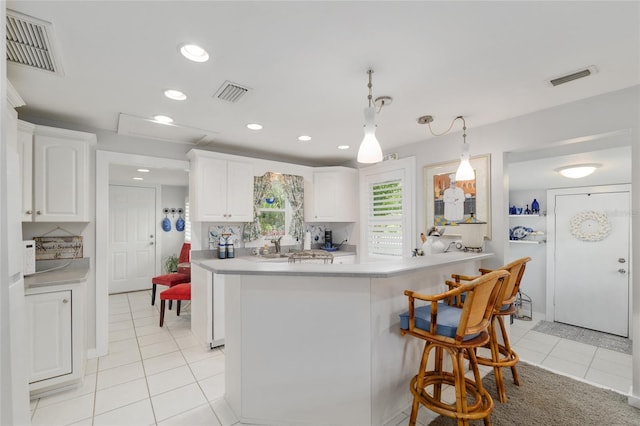 12335 SE 130th Ct, Ocklawaha, FL 32179 - kitchen with light tile patterned floors, light countertops, a breakfast bar area, white cabinets, and hanging light fixtures