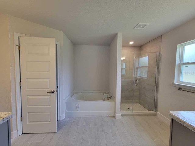 15055 SW 25th Cir, Ocala, FL 34473 - bathroom featuring vanity, wood finished floors, a garden tub, a shower stall, and baseboards