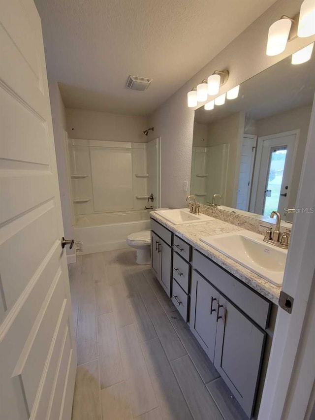 15055 SW 25th Cir, Ocala, FL 34473 - bathroom with double vanity, a textured ceiling, shower / washtub combination, toilet, and wood finished floors