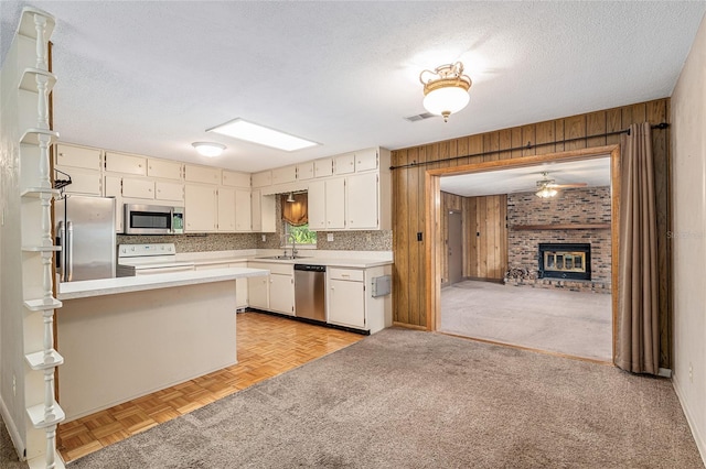 3621 SE 12th Pl, Ocala, FL 34471 - kitchen featuring appliances with stainless steel finishes, light countertops, wooden walls, a peninsula, and a brick fireplace