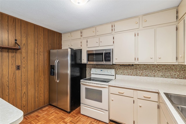 3621 SE 12th Pl, Ocala, FL 34471 - kitchen featuring appliances with stainless steel finishes, light countertops, wooden walls, a sink, and a textured ceiling
