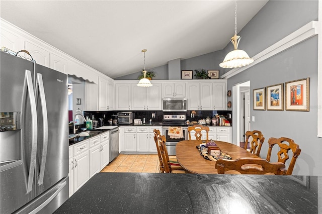 5445 NE Anthony Rd, Ocala, FL 34475 - kitchen with stainless steel appliances, decorative backsplash, lofted ceiling, light tile patterned floors, and white cabinets