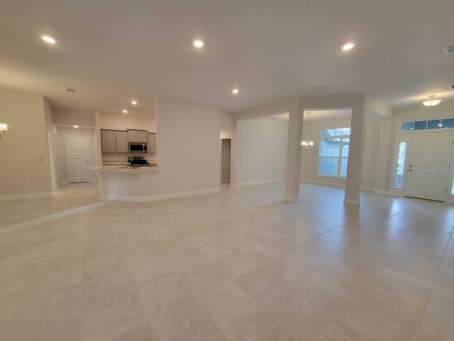 13977 SW 81st St, Dunnellon, FL 34432 - unfurnished living room featuring recessed lighting, baseboards, a chandelier, ornate columns, and light tile patterned floors