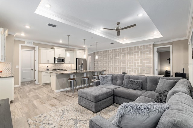 8878 SW 103rd Cir, Ocala, FL 34481 - living room featuring a raised ceiling, ceiling fan, crown molding, recessed lighting, and light wood-style flooring