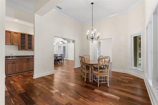 659 NW 155th Way, Newberry, FL 32669 - dining room featuring a chandelier, arched walkways, dark wood-style floors, a towering ceiling, and crown molding