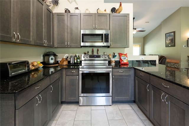 13850 SE 73rd Ln, Morriston, FL 32668 - kitchen featuring stainless steel appliances, light tile patterned flooring, dark stone countertops, a ceiling fan, and vaulted ceiling