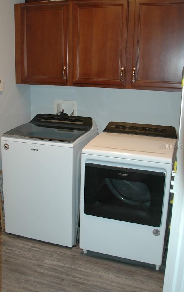 14126 Greater Pines Blvd, Clermont, FL 34711 - laundry area featuring washing machine and dryer, cabinet space, and wood finished floors