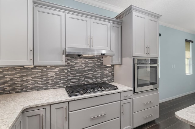 9805 SW 95th Loop, Ocala, FL 34481 - kitchen featuring appliances with stainless steel finishes, under cabinet range hood, ornamental molding, dark wood-style flooring, and decorative backsplash