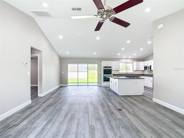 226 Locust Ln, Ocala, FL 34472 - kitchen featuring stainless steel appliances, dark countertops, open floor plan, white cabinetry, and a center island