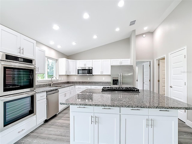 226 Locust Ln, Ocala, FL 34472 - kitchen with stainless steel appliances, vaulted ceiling, stone countertops, white cabinets, and a kitchen island