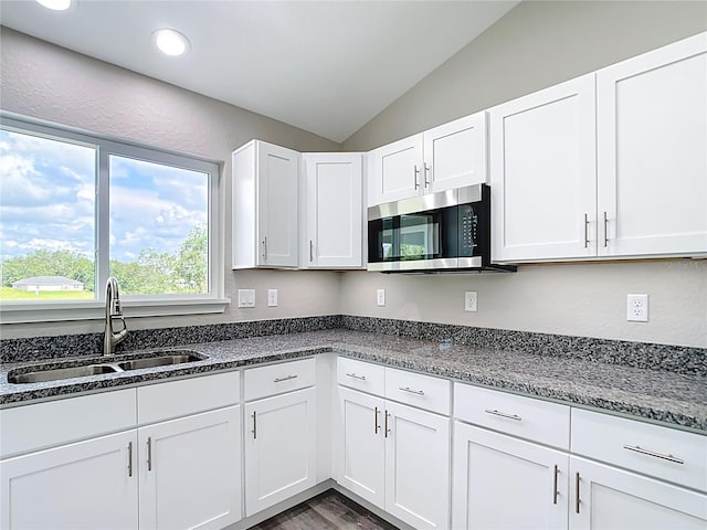 226 Locust Ln, Ocala, FL 34472 - kitchen with stainless steel microwave, lofted ceiling, white cabinetry, dark stone countertops, and wood finished floors