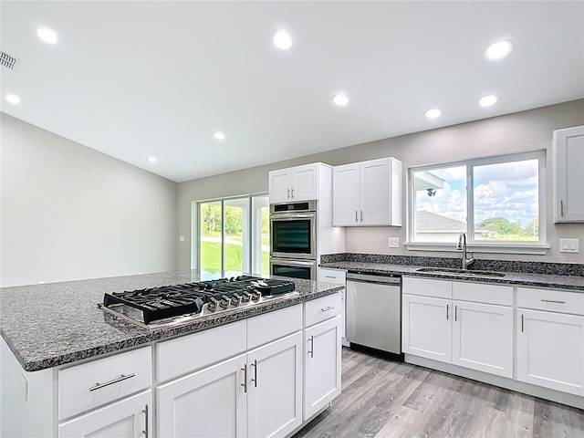 226 Locust Ln, Ocala, FL 34472 - kitchen with appliances with stainless steel finishes, dark stone countertops, light wood-style flooring, recessed lighting, and white cabinets