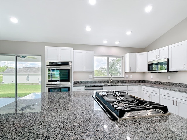 226 Locust Ln, Ocala, FL 34472 - kitchen with stainless steel appliances, dark stone counters, white cabinets, lofted ceiling, and recessed lighting