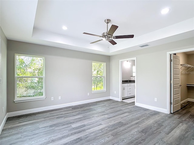 226 Locust Ln, Ocala, FL 34472 - unfurnished bedroom featuring a walk in closet, dark wood-style floors, a tray ceiling, recessed lighting, and connected bathroom