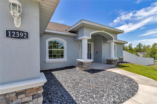 12392 SW 85th Pl, Dunnellon, FL 34432 - view of exterior entry with stone siding, a shingled roof, and stucco siding