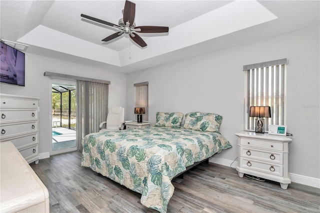 12392 SW 85th Pl, Dunnellon, FL 34432 - bedroom featuring access to outside, a tray ceiling, wood finished floors, and a ceiling fan