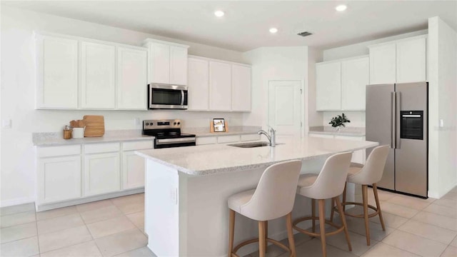 4508 SW 56th Pl, Gainesville, FL 32608 - kitchen with stainless steel appliances, a sink, a center island with sink, a breakfast bar area, and white cabinets