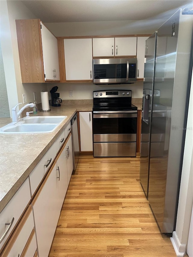 9255 SW 90th Ct Unit B, Ocala, FL 34481 - kitchen featuring stainless steel appliances, a sink, light wood-type flooring, and white cabinets