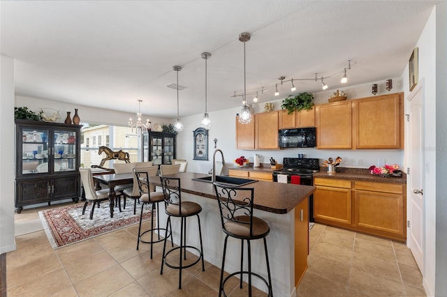 6646 SW 64th Ave, Ocala, FL 34476 - kitchen featuring black appliances, dark countertops, a chandelier, a breakfast bar, and a kitchen island with sink
