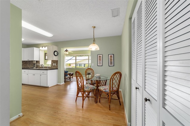 8431 SW 93rd Pl Unit F, Ocala, FL 34481 - dining area with light wood-type flooring, a textured ceiling, a ceiling fan, and baseboards