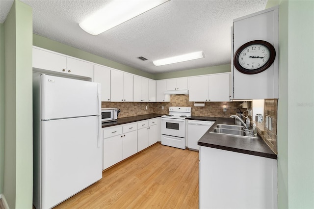 8431 SW 93rd Pl Unit F, Ocala, FL 34481 - kitchen featuring white appliances, a sink, under cabinet range hood, dark countertops, and light wood finished floors