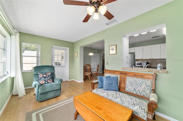 8431 SW 93rd Pl Unit F, Ocala, FL 34481 - living room with a textured ceiling, ceiling fan, light wood-style floors, and baseboards