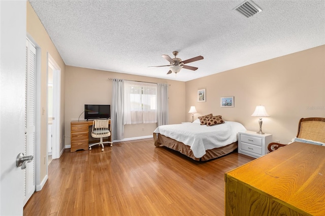 8431 SW 93rd Pl Unit F, Ocala, FL 34481 - bedroom featuring light wood finished floors, a textured ceiling, a desk, ceiling fan, and baseboards