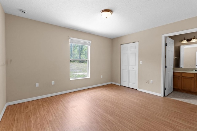 23340 NW Columbine Ave, Dunnellon, FL 34431 - unfurnished bedroom featuring light wood-style flooring, baseboards, a closet, and ensuite bathroom