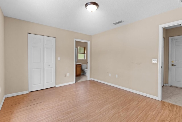23340 NW Columbine Ave, Dunnellon, FL 34431 - unfurnished bedroom with light wood-style floors, a closet, baseboards, and ensuite bath