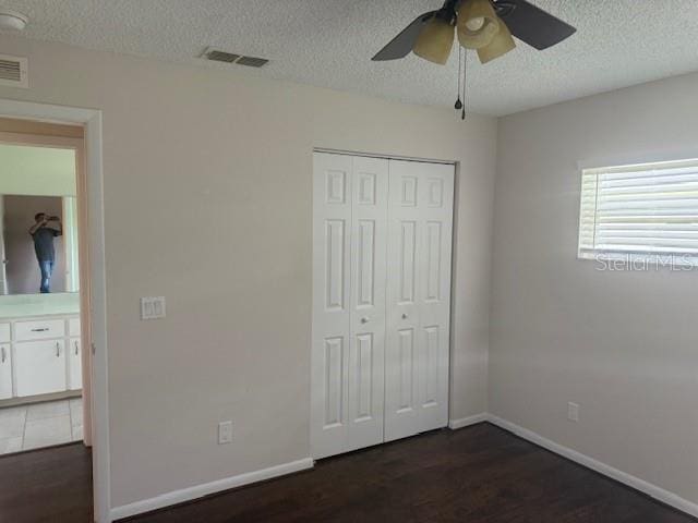 9722 SW 95th Ct Unit C, Ocala, FL 34481 - unfurnished bedroom with a textured ceiling, dark wood-style floors, a closet, and ceiling fan
